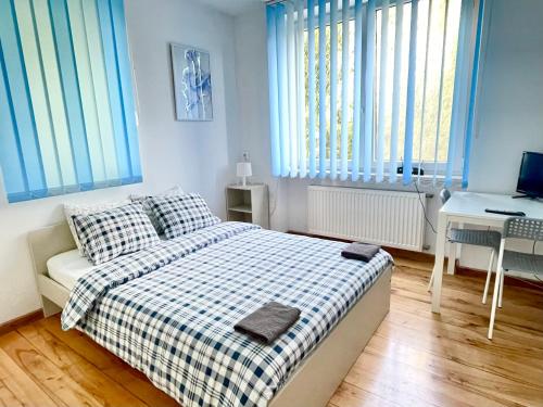 a bedroom with a bed and a desk and windows at Pokoje Slawin in Lublin