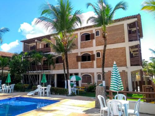 un edificio con palmeras y piscina en San Bernardo Apart-Hotel, en Alcobaça