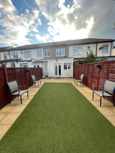 a patio with chairs and a lawn in front of a house at The Peaceful Place in Cheshunt