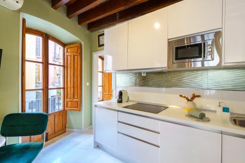 een keuken met witte kasten en een magnetron bij Aile Granada - Hostatel in Granada