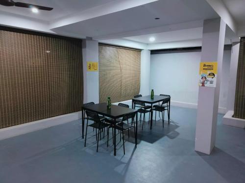 3 tables et chaises noires dans une pièce avec écran dans l'établissement Alohaa Homestel, à Coimbatore
