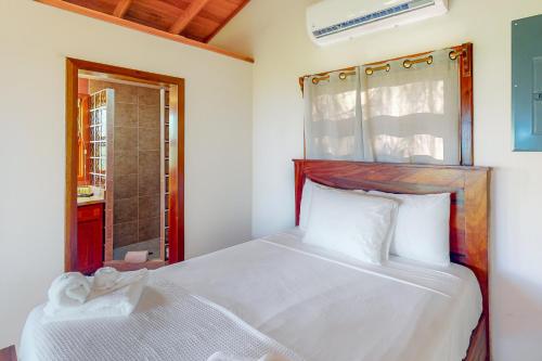 a bedroom with a white bed and a bathroom at The Cottages at Island Pearl Gold Standard Certified in Caye Caulker