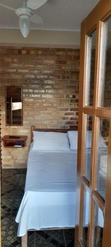 a bedroom with a white bed and a brick wall at San Bernardo Apart-Hotel in Alcobaça