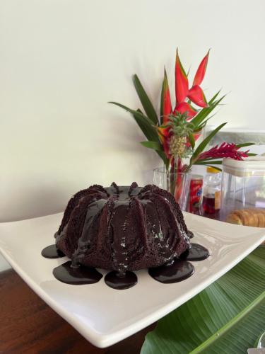 a chocolate cake on a plate with a vase of flowers at Pousada Aconchego in Caraíva