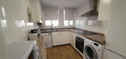 a kitchen with white cabinets and a washer and dryer at Balcón Playa Delicias in Águilas