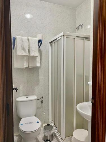 a white bathroom with a toilet and a sink at Hostal Casa López in La Zarza