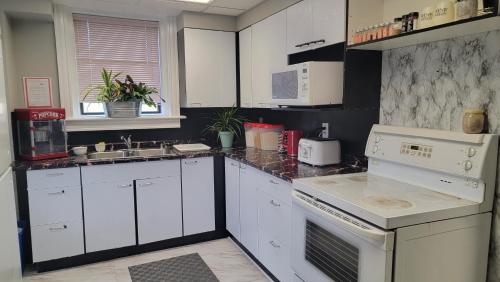 a kitchen with white cabinets and white appliances at Planet M Hostel in Niagara Falls