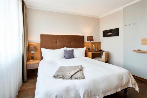 a bedroom with a large white bed with a brown headboard at Victoria - Alpine Boutique Hotel & Fine Dining in Meiringen
