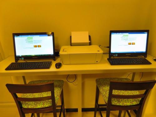 two laptops and a printer on a desk with chairs at Grand Hotel in Reconquista