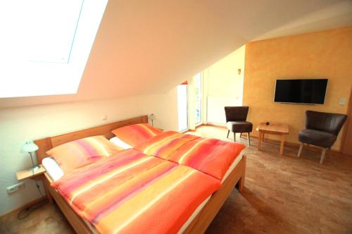 een slaapkamer met een bed, een tv en een stoel bij Gästehaus Jäger in Gersfeld