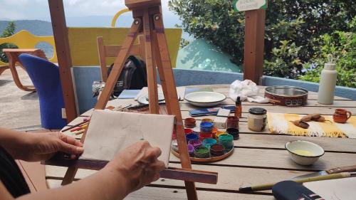 a person painting a piece of paper on a table at El Encinal de las Flores in Valle de Bravo