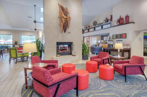 a lobby with red chairs and a fireplace at Hampton Inn & Suites Wilmington/Wrightsville Beach in Wilmington