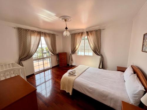 a bedroom with a white bed and two windows at Classic Tranquil Madeiran 4-Bedroom Villa Funchal in Funchal