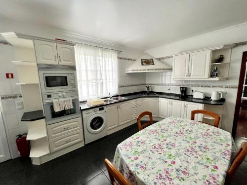 a kitchen with white cabinets and a table and a sink at Classic Tranquil Madeiran 4-Bedroom Villa Funchal in Funchal