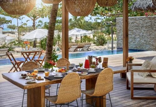 an outdoor dining area with a table and chairs and a pool at Villa Alegria - La Villa Group in Jericoacoara