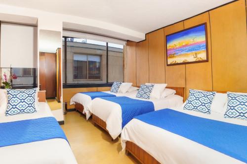 Habitación con 3 camas con sábanas azules y blancas. en Hotel San Francisco, en Tunja