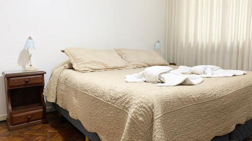 a bed with white towels on it with a night stand at Administracion Callao in Buenos Aires