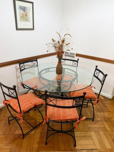 a glass table with four chairs and a vase on it at Administracion Callao in Buenos Aires