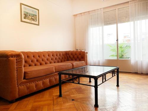 a living room with a brown couch and a glass table at Administracion Callao in Buenos Aires