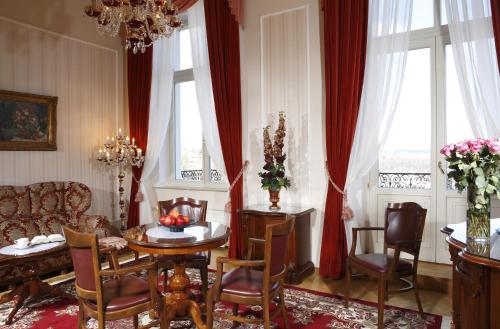 a living room with a table and chairs and windows at Bristol Palace in Karlovy Vary