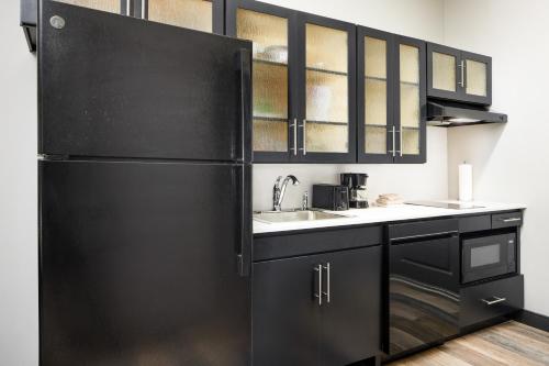 a black kitchen with a sink and a refrigerator at Candlewood Suites - Lebanon by IHG in Lebanon