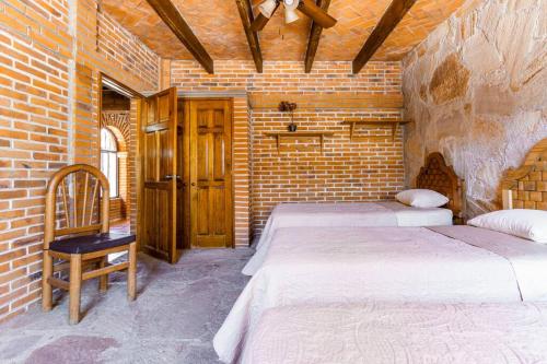 une chambre avec deux lits et un mur de briques dans l'établissement Casa De Piedra, à Tequisquiapan