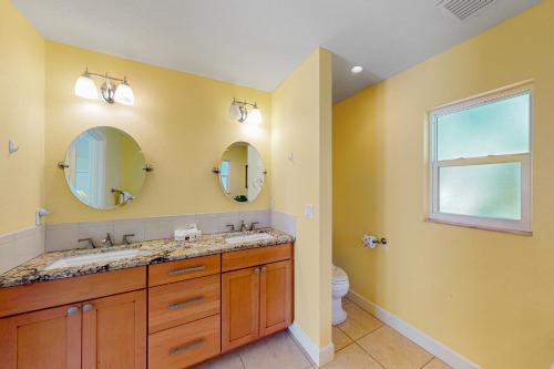 a bathroom with two sinks and two mirrors at Coquina Sands in Holmes Beach