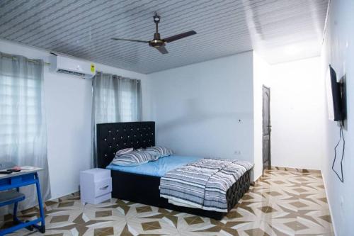 sypialnia z łóżkiem i wentylatorem sufitowym w obiekcie Holly House w mieście Oshien