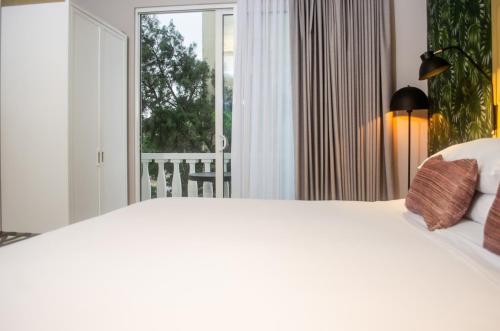 a white bed in a room with a window at Faranda Collection Barranquilla, a member of Radisson Individuals in Barranquilla