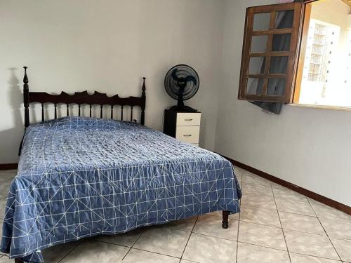 a bedroom with a bed with a blue comforter and a window at Praia dos Milionários in Ilhéus