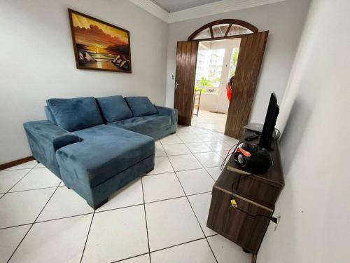 sala de estar con sofá azul y TV en Praia dos Milionários, en Ilhéus