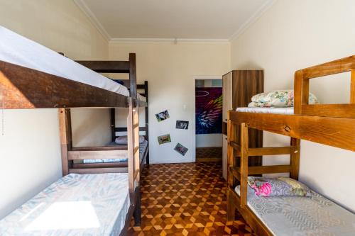 a room with three bunk beds and a hallway at Hostel Capivara's Lounge Bar in Curitiba