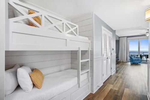 a white bedroom with a bunk bed and a living room at Calypso 3-2210 - Love Nest in Panama City Beach