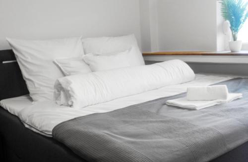 Una cama con almohadas blancas y un ordenador portátil. en Relax Oasis with 65 SmartTV, Kitchen and Balcony, en Duisburg