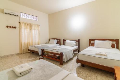 Cette chambre comprend 3 lits et une fenêtre. dans l'établissement HOTEL MONTANAR HOME, à La Dorada
