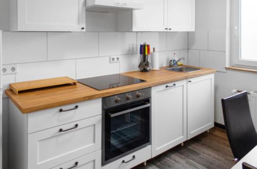 a kitchen with white cabinets and a wooden counter top at Relax Oasis with 65 SmartTV, Kitchen and Balcony in Duisburg