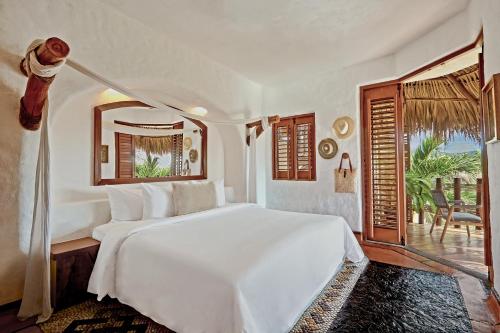 a bedroom with a large white bed and a window at La Villa Luz (sólo adultos) in Zihuatanejo