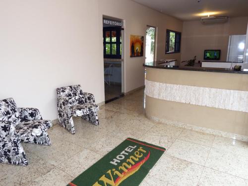 a lobby with two chairs and a bar with a counter at Hotel Winner in Barretos