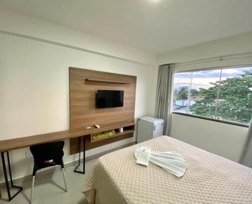 een slaapkamer met een bed, een bureau en een televisie bij Hotel Skalla in Teixeira de Freitas