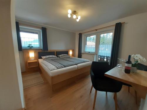 Schlafzimmer mit einem Bett, einem Schreibtisch und Fenstern in der Unterkunft Gästehaus Staller in Ruhpolding