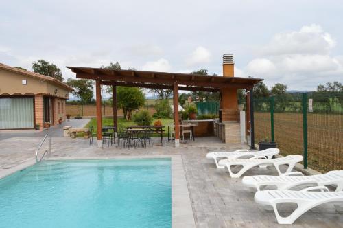 a swimming pool with chairs and a gazebo at Mas Piua in Girona
