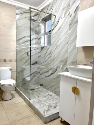 a bathroom with a shower with a toilet and a sink at 101 Camarque - 3 Bedroom Beachfront Apartment In Umdloti - 180 Degree Sea Views in Umdloti