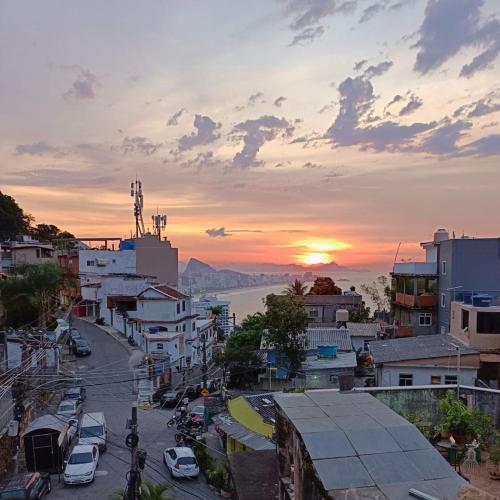 a city with cars parked on a street at sunset at Apêzinho Vidigal - RJ in Rio de Janeiro