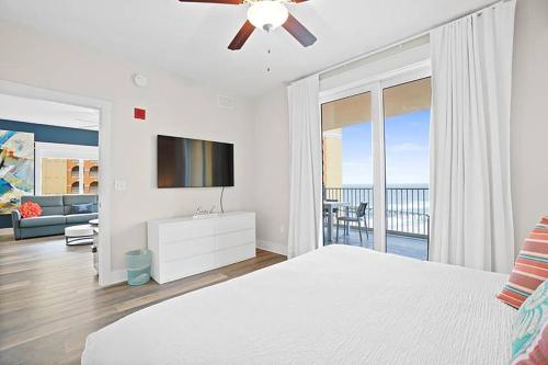 um quarto com uma cama, uma televisão e uma varanda em Calypso 3-1601 - Corine's Corner em Panama City Beach