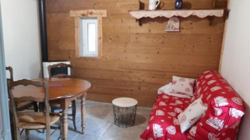sala de estar con mesa y sofá rojo en Le petit grenier en Saint-Bonnet-en-Champsaur