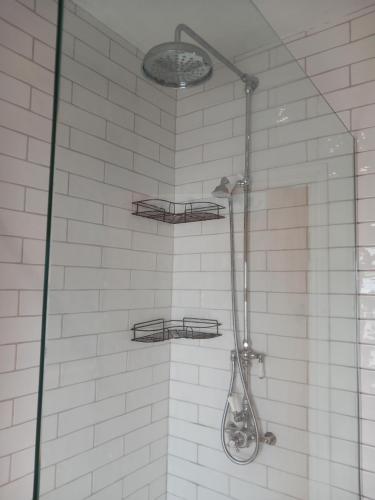 a shower with two shelves on a white tiled wall at Seashells, Newry, Anglesey - Ideal for the ferry crossing to Ireland in Holyhead