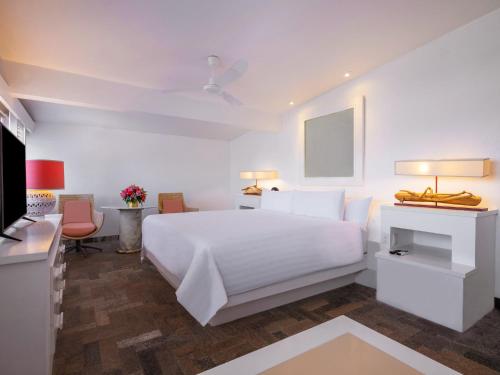 a white bedroom with a white bed and a desk at Las Brisas Acapulco in Acapulco