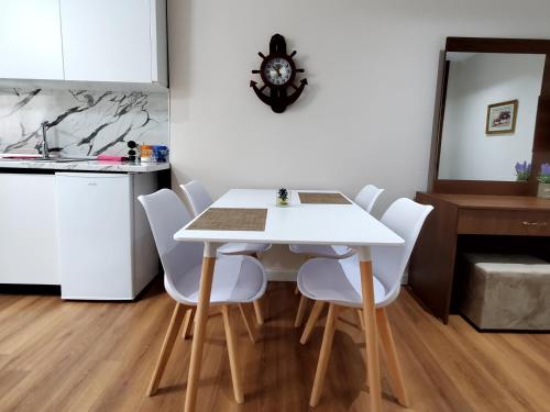 a white dining room table with white chairs and a clock at Armando's house Durres in Durrës