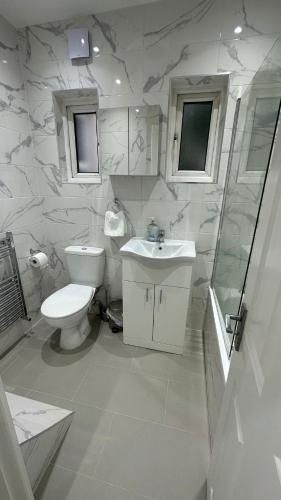 a white bathroom with a toilet and a sink at 179 church Road in London