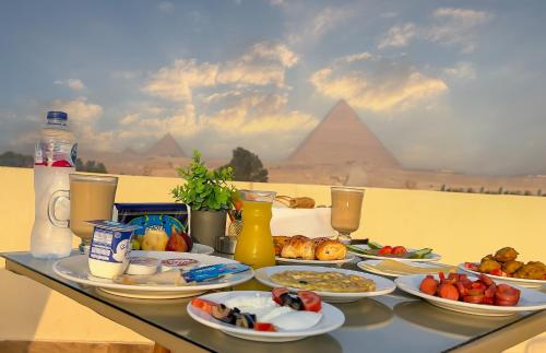 una mesa con platos de comida en ella con pirámides en Pyramids Glory INN, en El Cairo